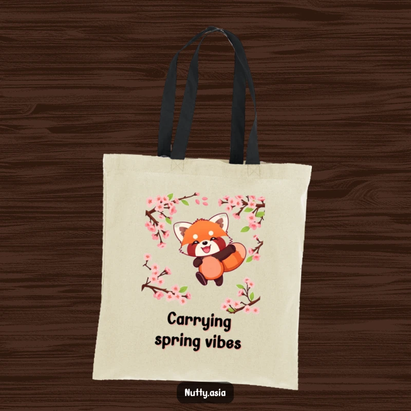 Playful red panda leaping through cherry blossoms, a stylish and humorous tote bag.